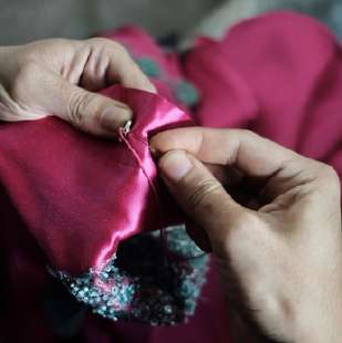 Hand-sewing embellishments on pink fabric